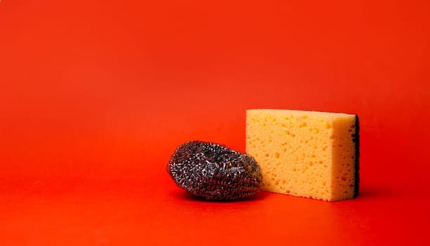 sponge and metal mesh for cleaning on a red background.