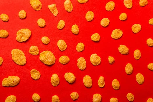 background of corn flakes on a red background top view.