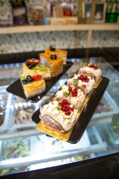 dessert on a cooking showcase. cake with berries on a black plate