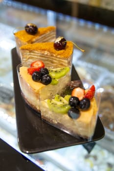 dessert on a cooking showcase. cake with berries on a black plate