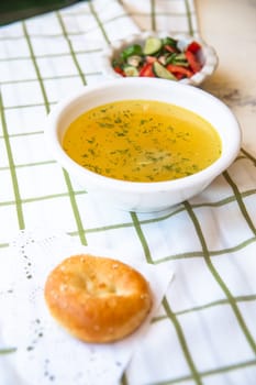 homemade chicken soup with white bread and salad. Lunch on a white tablecloth