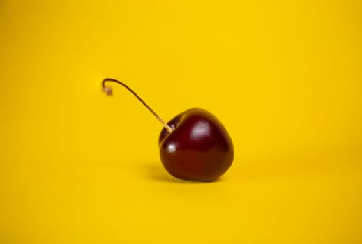 red cherry close-up on a yellow background