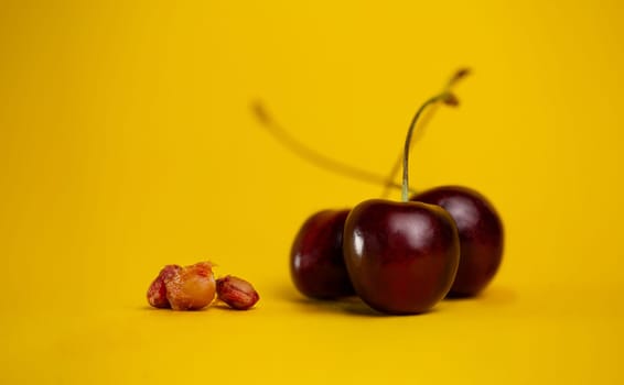 ripe cherries with pits on a yellow background.