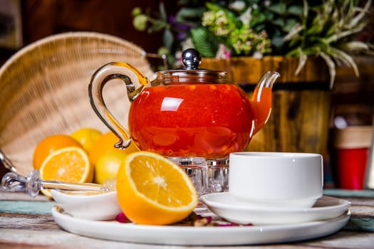 red buckthorn tea in a kettle and a cup of oranges