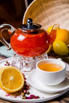 a cup of buckthorn tea in a glass teapot on the table