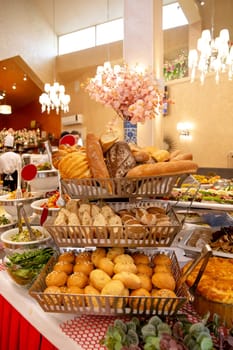a counter with bread products on a buffet table in a restaurant.
