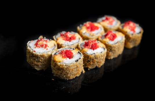 baked japanese rolls with red caviar on a black background.