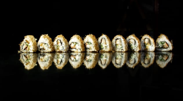 triangular japanese sushi in a row on a black background with reflection.