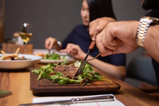 man in the cafe eats beef steak with greens close-up.