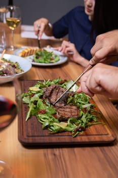 man in the cafe eats beef steak with greens close-up.