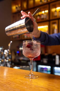 Bartender prepares a cocktail with berries at the bar