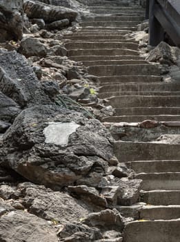 Old Concrete Steps and Roadside Rocks leading up a Hill in the Forest. Space for text, Selective focus.