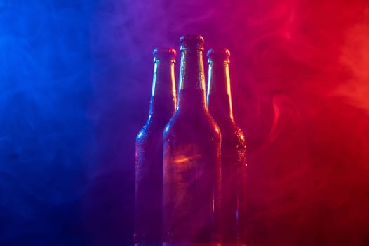 Three bottles of beer in a blue-pink mist