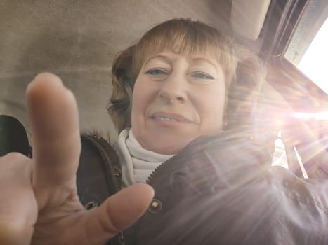 Middle aged woman in a car taking a selfie while enjoying a drive. Female mature driver posing inside car. Funny happy tourist girl in alone travel