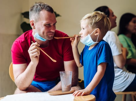 Father and son eat chocolate dessert with spoons in Cafe. Spending time together. Sweet tooth. Happy childhood.