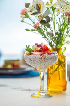 Chia seed pudding with fresh fruit in glass on white table with blurred background. Healthy eating, dieting, or detox concept.