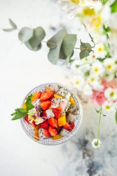 Chia seed pudding with strawberries, mango, dragon fruit in glass on marble table. Healthy vegetarian breakfast or snack.