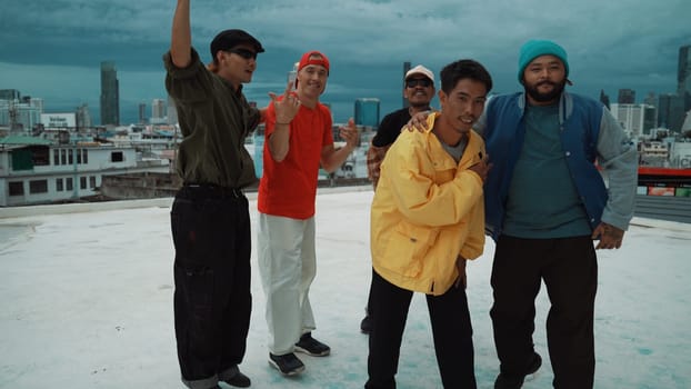 Skilled multicultural street dancing group pose at camera at roof top while moving to the rhyme and music. Young people or teenager moving to funky music, break dance. Outdoor sport 2024. Endeavor.