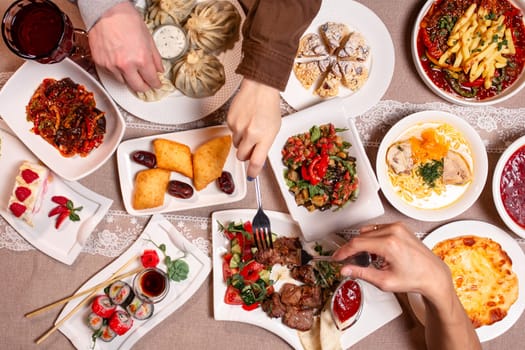 top view of the different dishes on the table. hands reaching for food.