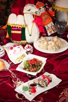 A variety of sushi rolls, along with other assorted dishes, are arranged on a table with a red tablecloth.