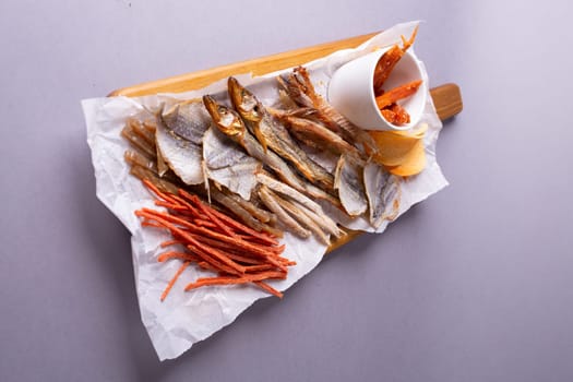 A variety of dehydrated fish, carrots, and pumpkin slices on a white paper over grey background. Isolated on a grey background.