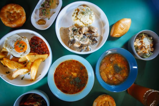 Top view of a table full of delicious traditional russian food with beer and bread. There are 6 different plates on the table.