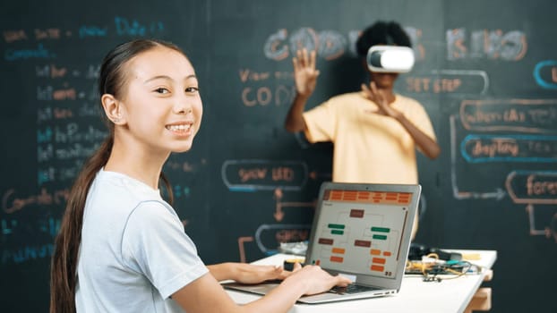 African boy using VR glasses while young woman looking at camera and coding or programing system. Smart teenager standing at blackboard while touching in simulate program at STEM class. Edification.