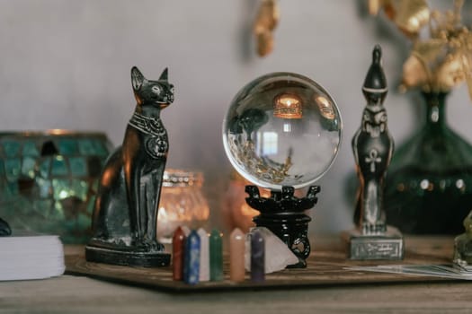 An atmospheric setting featuring a crystal ball, Egyptian cat statues, candles, and crystals, creating a mystical ambiance