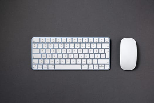 Top view of wireless keyboard and mouse on dark gray work desk