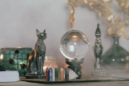 An atmospheric setting featuring a crystal ball, Egyptian cat statues, candles, and crystals, creating a mystical ambiance