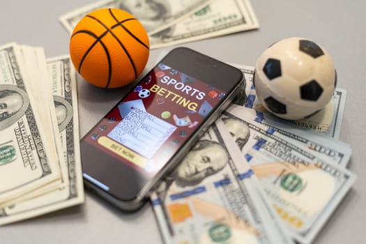 Smartphone with gambling mobile application and basketball ball with money close-up. Sport and betting concept. High quality photo