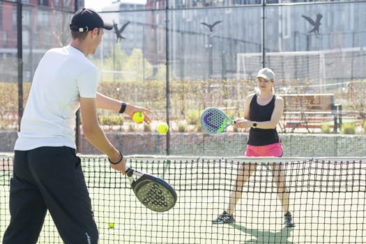 Ukraine Kyiv, April 02 2024. Happy athletic couple having fun while playing padel tennis doubles match on outdoor court. . High quality photo