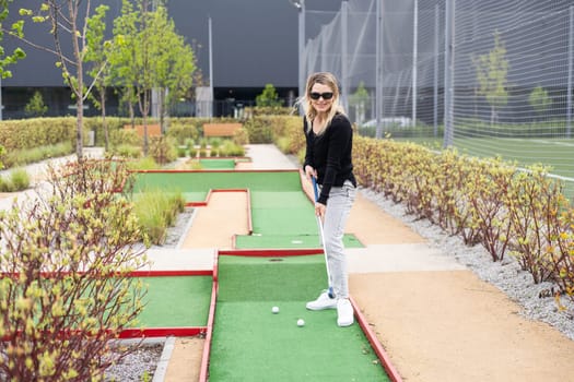 Woman playing mini golf at course. Summer sport and leisure activity. High quality photo