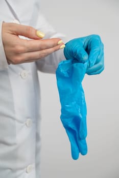 The doctor puts on latex gloves on a white background. Vertical photo
