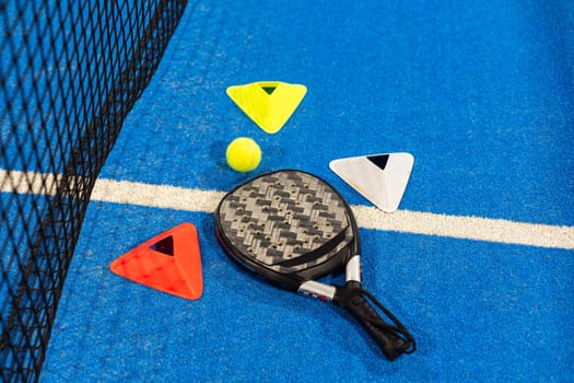 Black professional paddle tennis racket and ball with natural lighting on blue background. Horizontal sport theme poster, greeting cards, headers, website and app. High quality photo