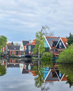 A tranquil body of water nestled among lush green trees and charming houses, creating a picturesque and idyllic scene of natural beauty old houses in Broek in Waterland in the Netherlands