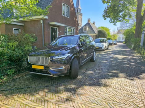 EV electric car charging in front of a house in the Netherlands, green energy and eco power produced from sustainable source to supply to charger station in order to reduce CO2 emission