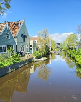 A peaceful river flows through a charming small town, surrounded by traditional houses on either side. Broek in Waterland Netherlands
