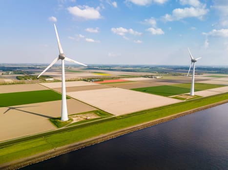 A mesmerizing aerial view of a wind farm in Flevoland, Netherlands, where towering windmills stand gracefully in the wind, generating renewable energy for the region.