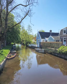A serene scene as a boat calmly rests on the riverbank under the shade of trees, surrounded by still water canals of the Dutch village Broek in Waterland Netherlands