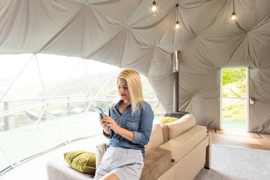 woman with smartphone in dome tent.