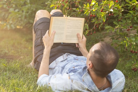 a man reads the Bible on the grass at a park.