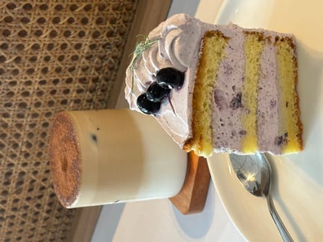 slice of blueberry cake decorated with fresh berries on white plate, delicious layered cake, top view in the cafe