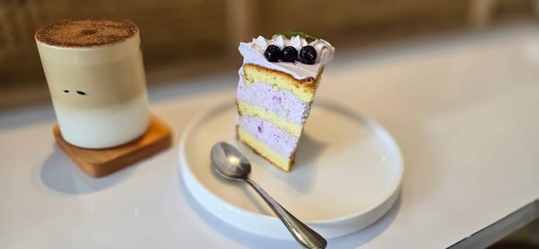 slice of blueberry cake decorated with fresh berries on white plate, delicious layered cake, top view in the cafe