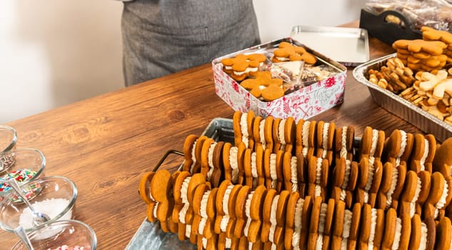 Denver, Colorado, USA-December 6, 2023-Making gingerbread man cookie sandwiches filled with eggnog buttercream, arrayed on a rustic wooden table, ideal for heartfelt Christmas gifting.