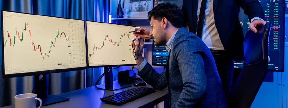 Stock exchange traders looking on high profit chart investment in panorama view, analyzing on monitor at night. Concept of discussing financial technology growth in neon light at workplace. Sellable.