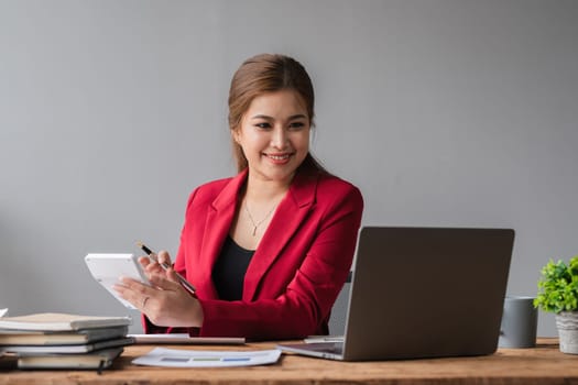 Beautiful accountant sitting working with laptop calculating financial and tax figures for company on desk in living room..