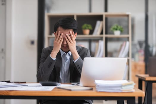 Unhappy young businessman feeling bored or disappointed while sitting in the office Distracted male employee feeling tired from monotonous work.