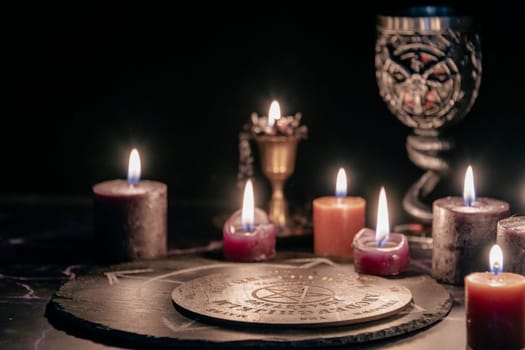 An eerie occult ritual setup featuring lit candles, a mystical symbol on slate, and a ceremonial goblet in a dark, moody setting