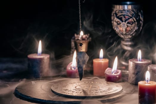 An eerie occult ritual setup featuring lit candles, a mystical symbol on slate, and a ceremonial goblet in a dark, moody setting